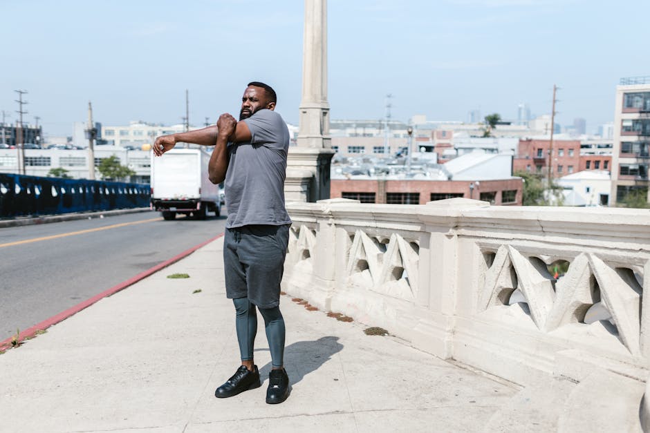 Athletic man stretching on a city bridge during an outdoor exercise session.