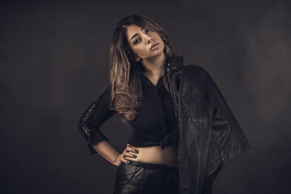 Stylish woman in black leather posing confidently in studio setting.