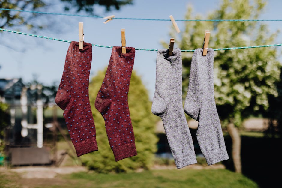 Soft focus of washed multicolored socks hanging on rope with clothespins outdoors on sunny summer day against natural background
