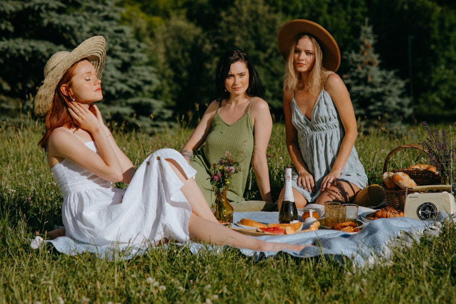 Three women enjoy a stylish summer picnic outdoors on a sunny day.