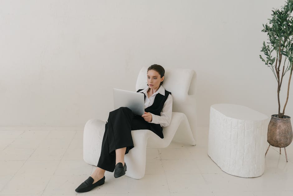 Businesswoman in a modern, minimalist setting working on a laptop indoors.